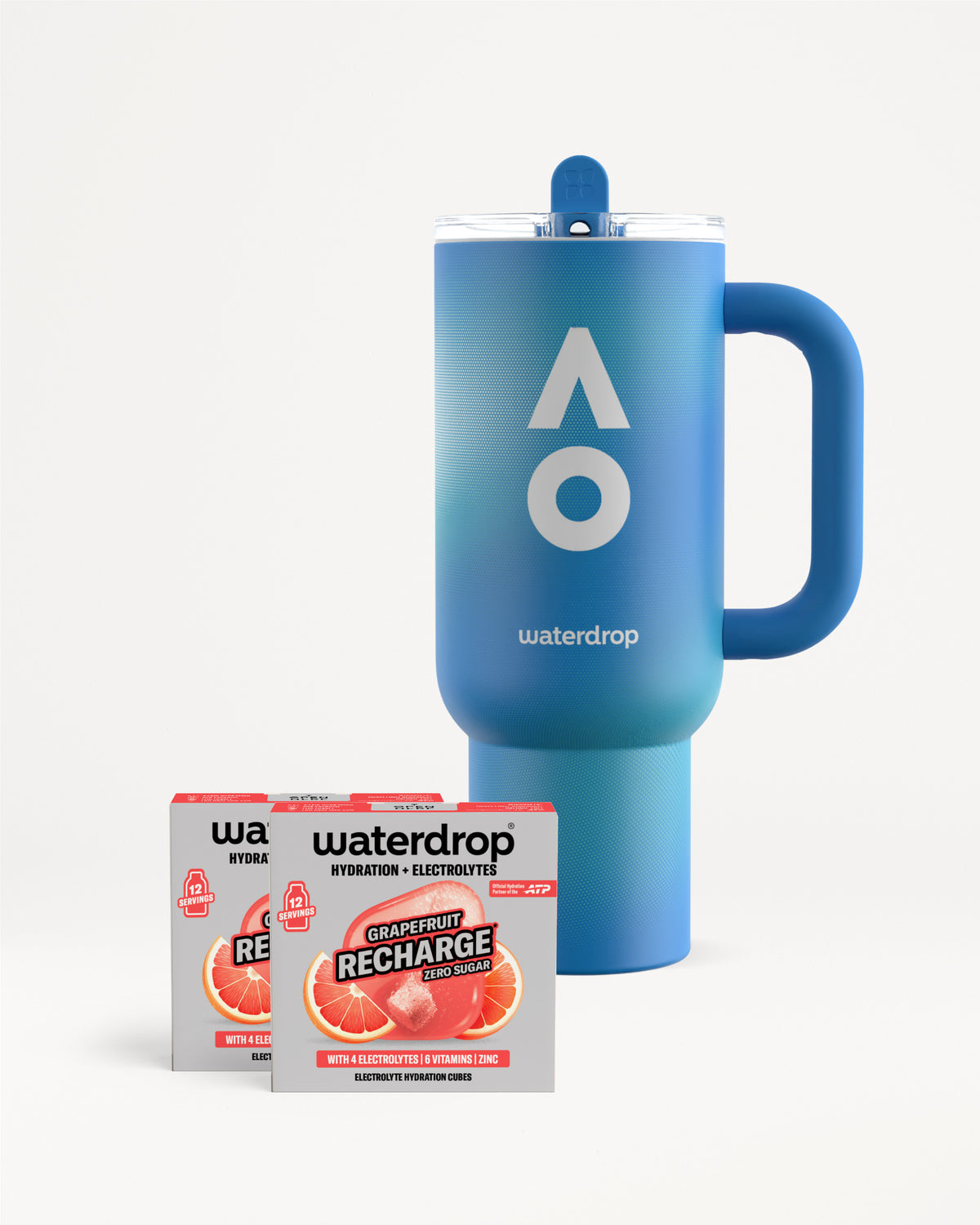 Kék waterdrop termoszbögre fogantyúval és tetővel, mellette két Grapefruit Recharge cukormentes doboz, dobozonként 12 adaggal, fehér háttéren.