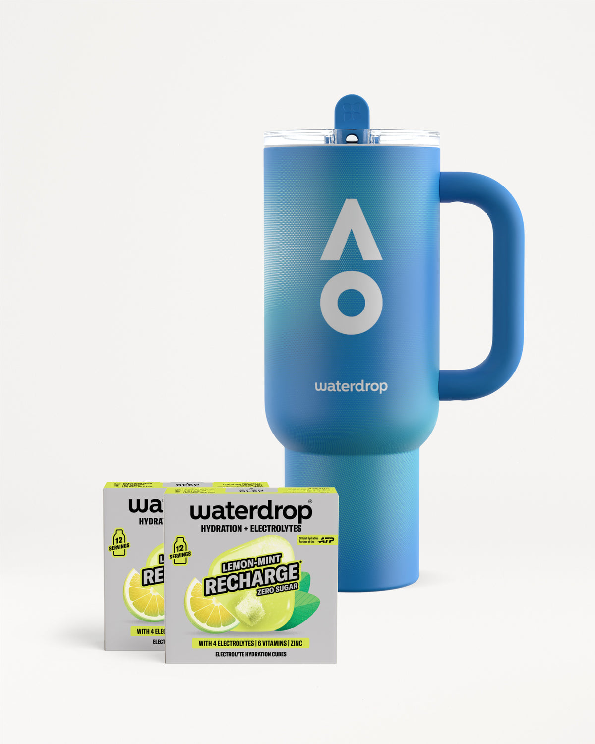 Kék waterdrop termoszbögre fogantyúval és tetővel, mellette két Lemon-Mint Recharge cukormentes doboz, dobozonként 12 adaggal, fehér háttéren.