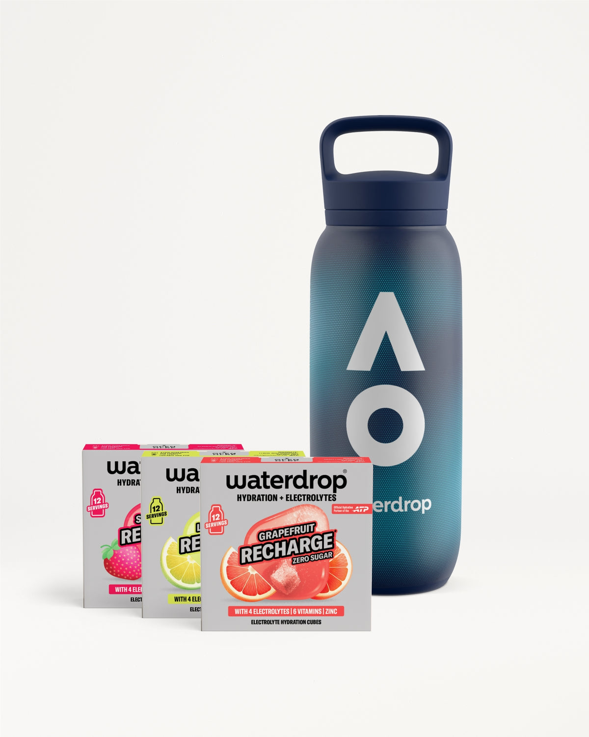 Sötétkék waterdrop újrahasználható palack fogantyús kupakkal, mellette három cukormentes Recharge doboz Strawberry, Lemon-Mint és Grapefruit ízben, dobozonként 12 adaggal, fehér háttéren.