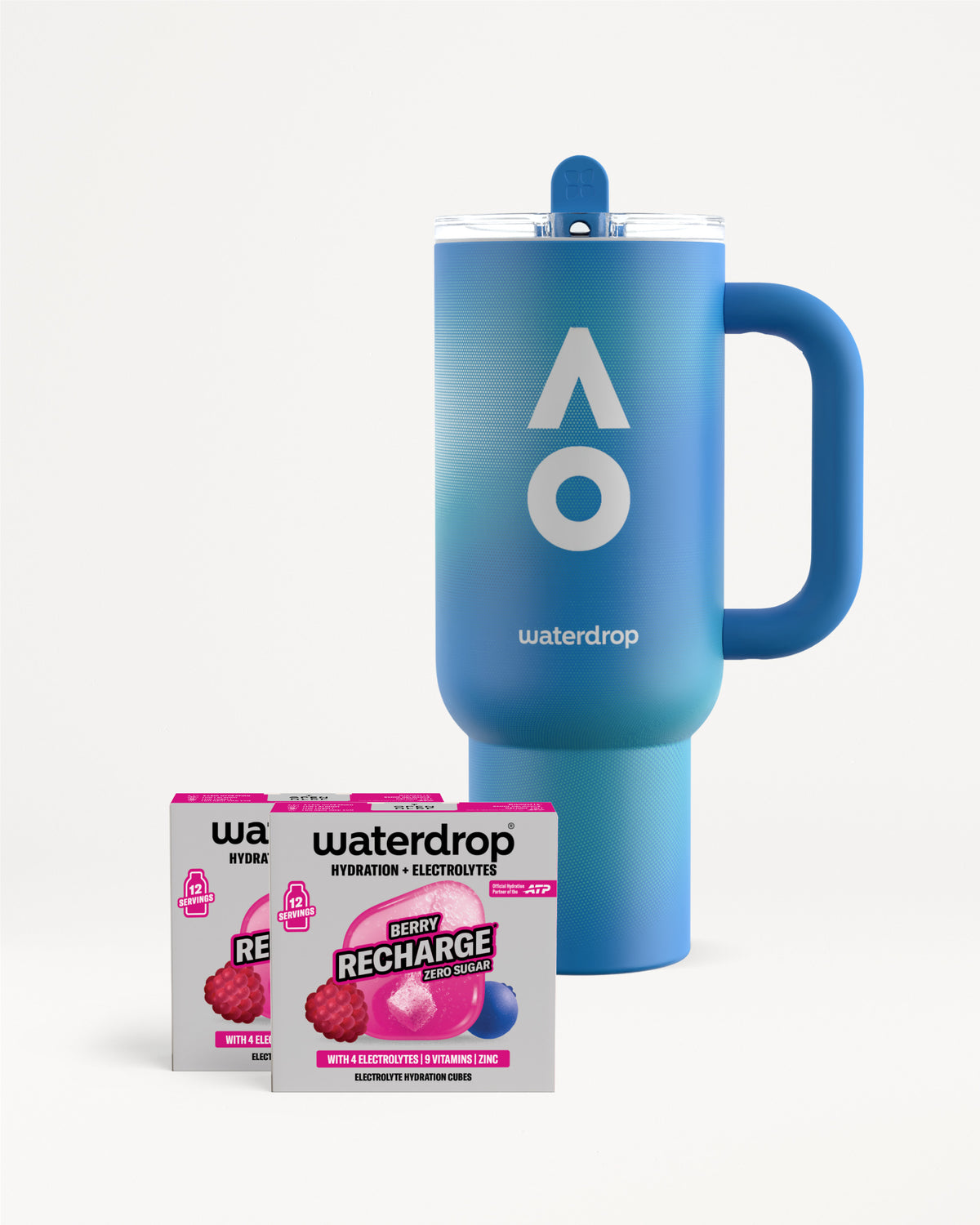 Kék waterdrop termoszbögre fogantyúval és tetővel, mellette két Berry Recharge cukormentes doboz, dobozonként 12 adaggal, fehér háttéren.