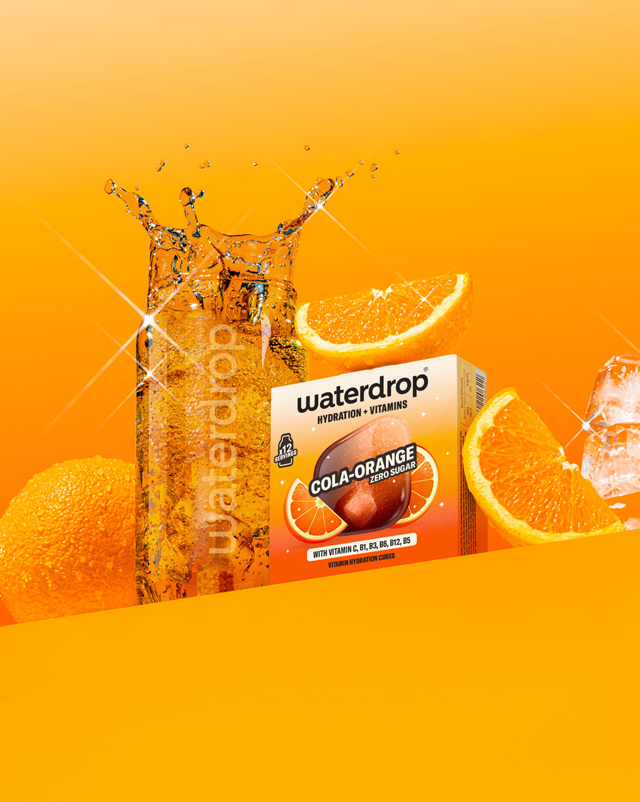 Waterdrop üvegpalack szénsavas itallal a Cola Orange ízesítésű doboz mellett, narancsokkal, jéggel és fröccsenő vízcseppekkel, narancssárga háttér előtt.