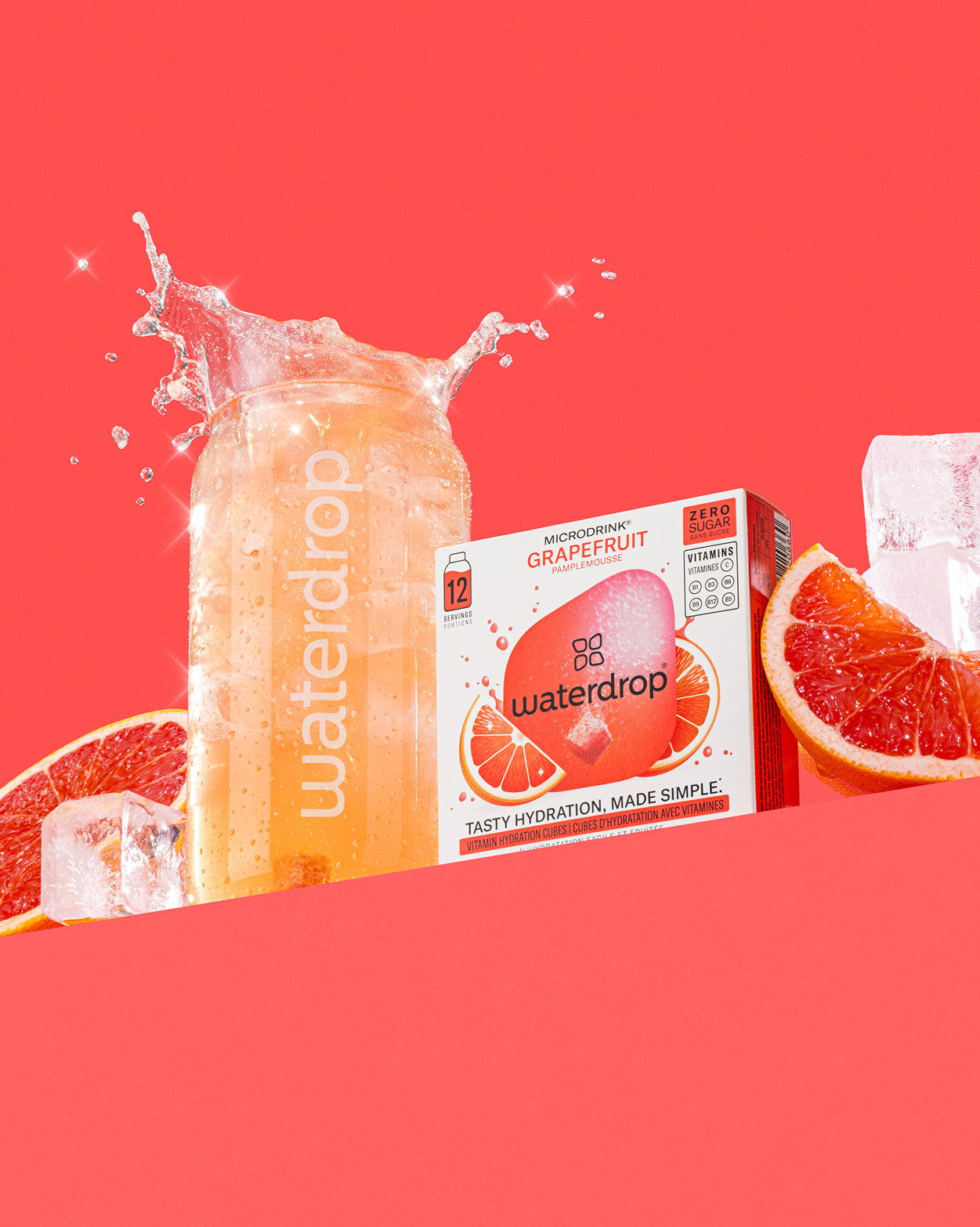Waterdrop üvegpalack szénsavas itallal a Microdrink Grapefruit doboz mellett, grapefruitszeletekkel, jéggel és fröccsenő vízzel, piros háttér előtt.