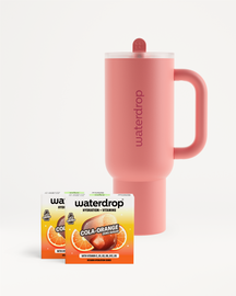 Rózsaszín Waterdrop termoszpohár fedéllel és szívószállal, két Cola Orange ízesítésű doboz mellett, fehér háttér előtt.