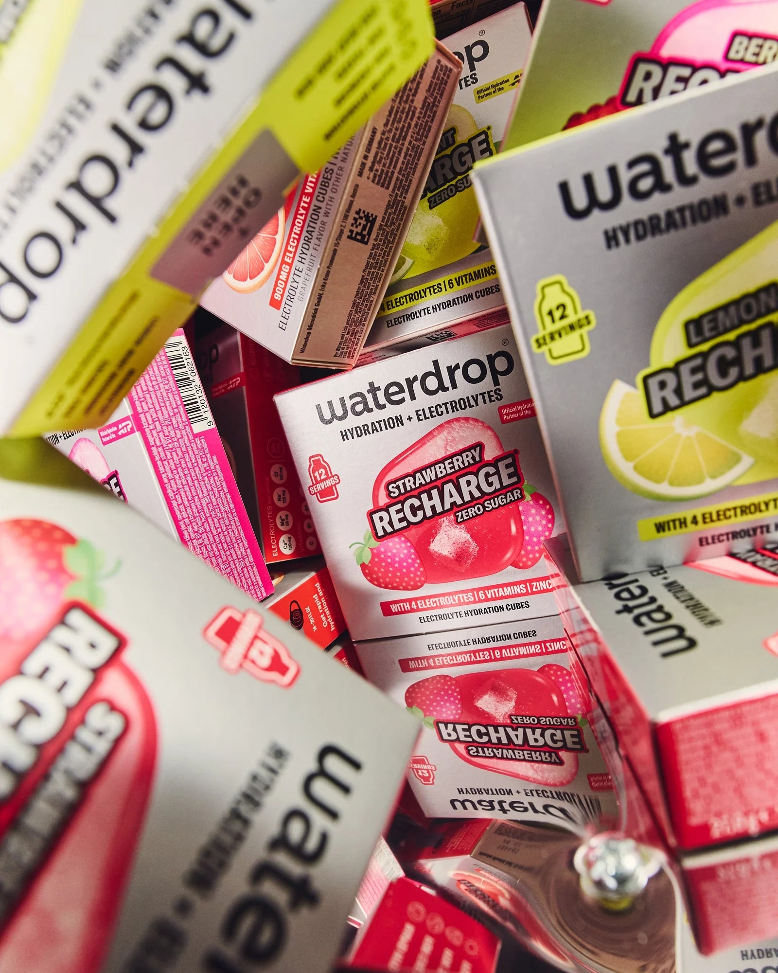 Különböző ízű waterdrop Recharge hidratáló kocka dobozok szorosan egymásra rendezve, többek között Strawberry és Lemon-Mint változatokkal.