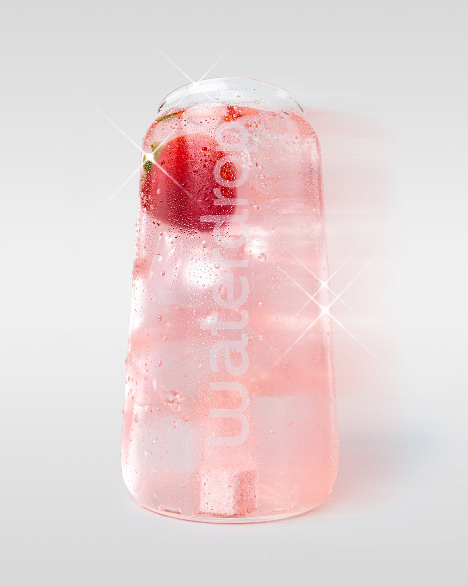 Waterdrop pohár rózsaszín itallal, jégkockákkal, piros gyümölccsel és egy látható hidratáló kockával, világos háttéren.