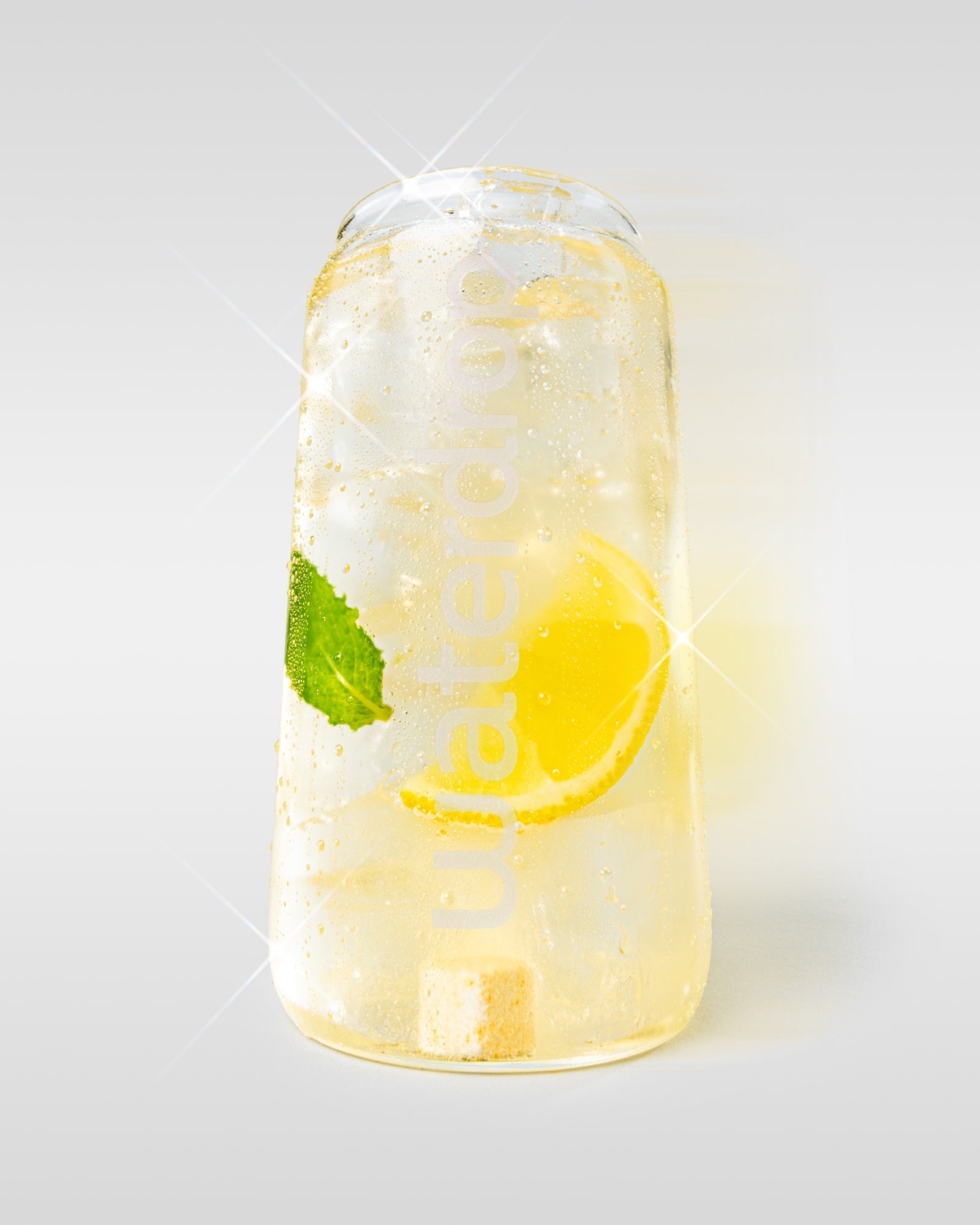 Waterdrop pohár Lemon-Mint itallal, citromszelettel, mentalevéllel és egy látható hidratáló kockával, világos háttéren.