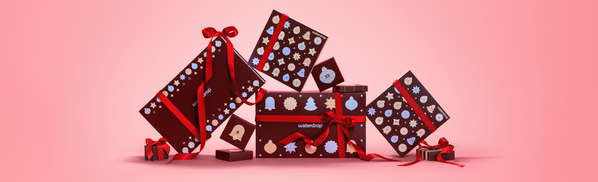 Assorted gift boxes arranged in a festive display on a pink gradient background.