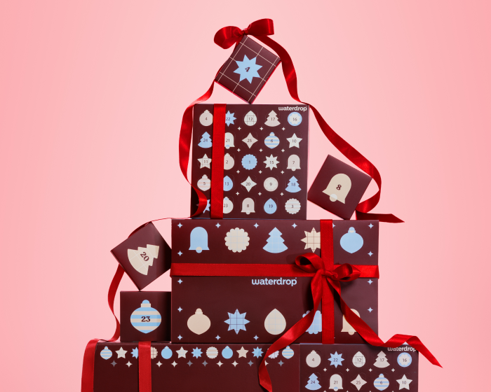 Motívumos díszdobozok piros szalagokkal a rózsaszín hátterű.